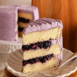 Slice of blueberry chiffon cake with purple frosting and blueberry jam filling.