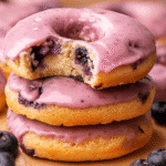 Stack of blueberry cake donut recipe with purple glaze and a bite taken