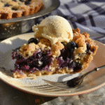 Slice of blueberry crumble cake topped with vanilla ice cream