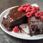 Flourless chocolate cake topped with fresh raspberries and glossy ganache