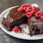 Flourless chocolate cake topped with fresh raspberries and glossy ganache