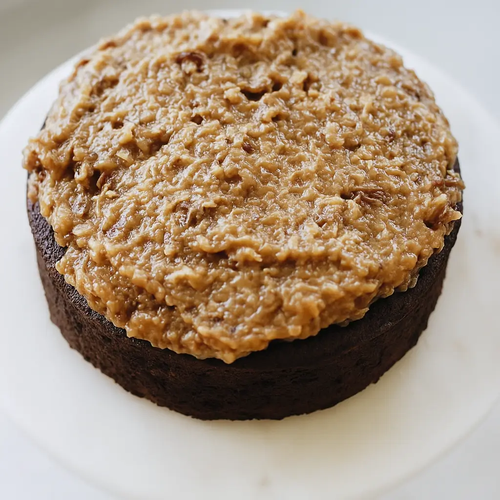 Coconut pecan frosting spread on chocolate cake